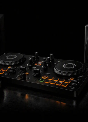 Pioneer DJ controller setup with a black 2-step DJ mixer, two matching studio monitors, and over-ear headphones on a glossy black surface against a dark background.